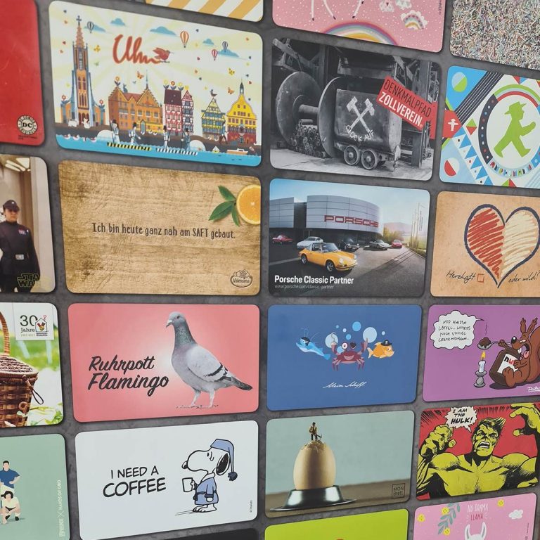Diverse bunte Frühstücksbrettchen mit verschiedenen Motiven und Texten auf einer Wand angeordnet.